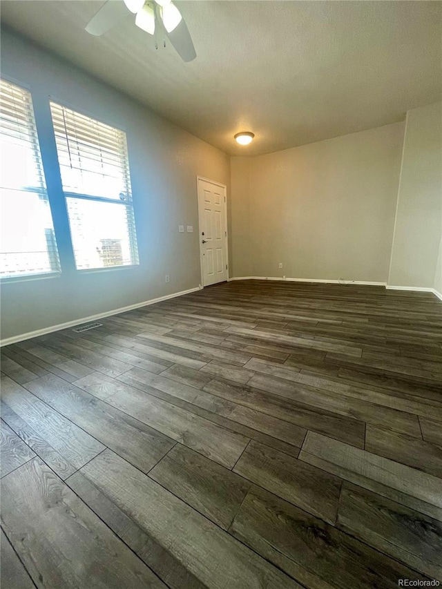 spare room with dark wood-style floors, baseboards, and a ceiling fan