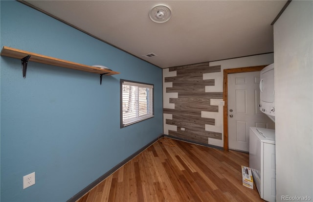 clothes washing area featuring stacked washer / dryer and hardwood / wood-style flooring