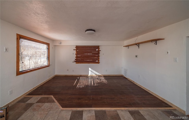 empty room with a textured ceiling and dark wood-type flooring