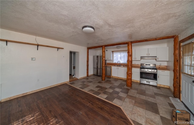 interior space with a textured ceiling, stainless steel appliances, white cabinetry, and sink