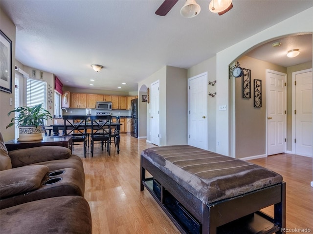 5369 Creek Way, Parker, CO 80134 - living area with arched walkways, light wood-style floors, a ceiling fan, and baseboards