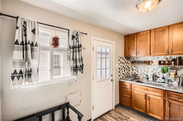 bar featuring a sink, light wood-style flooring, and backsplash