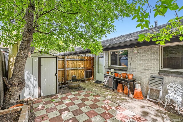 view of patio / terrace with a storage unit, fence, and an outdoor structure