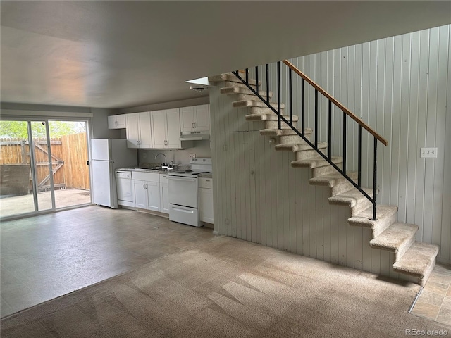 8682 W 51st Ave, Arvada, CO 80002 - kitchen with white appliances, white cabinets, under cabinet range hood, light carpet, and wood walls
