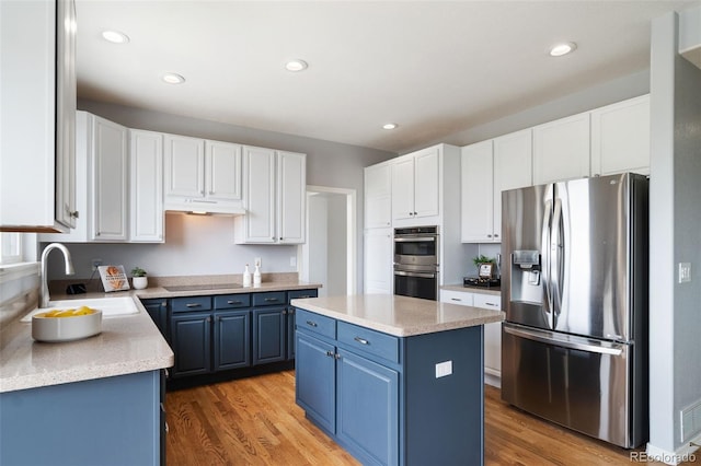20339 Vista Cir, Parker, CO 80138 - kitchen with stainless steel appliances, blue cabinetry, a center island, under cabinet range hood, and light wood-style floors