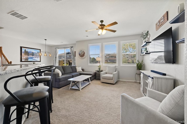 carpeted living room with ceiling fan with notable chandelier