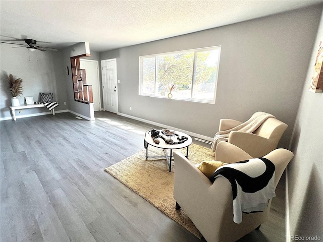 sitting room with ceiling fan, hardwood / wood-style floors, and a textured ceiling