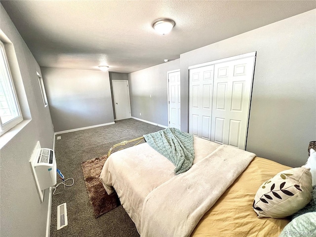 carpeted bedroom featuring a wall mounted air conditioner and a textured ceiling