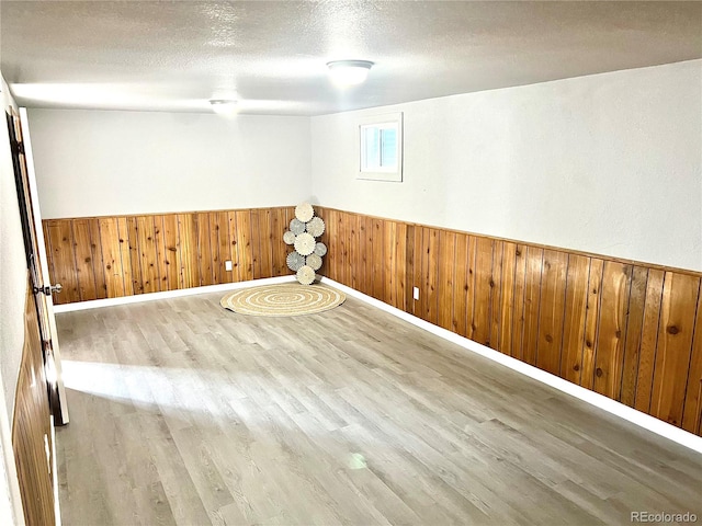 unfurnished room featuring wood-type flooring, a textured ceiling, and wooden walls