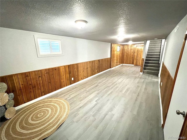 basement with hardwood / wood-style flooring, a textured ceiling, and wooden walls