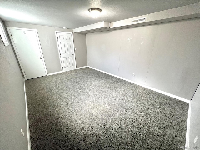 basement featuring dark carpet and a textured ceiling