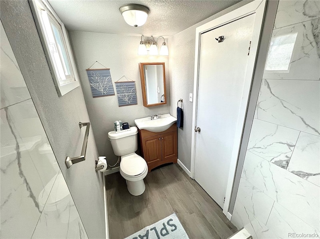 bathroom featuring vanity, wood-type flooring, a textured ceiling, and toilet