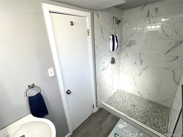 bathroom with a tile shower and hardwood / wood-style flooring