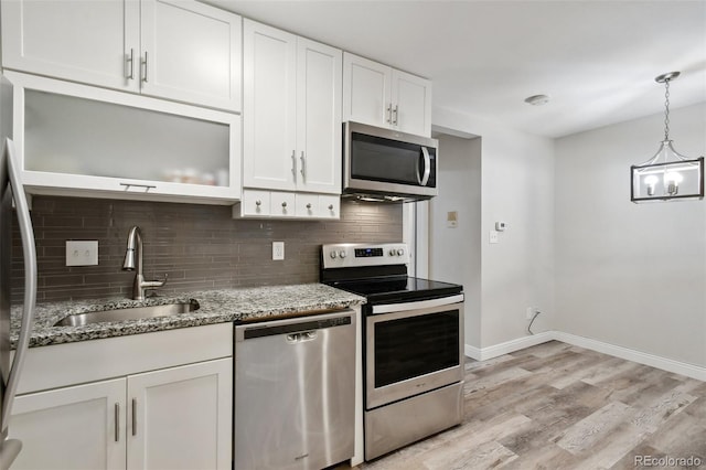 5875 E Iliff Ave Unit 108, Denver, CO 80222 - kitchen featuring stainless steel appliances, a sink, backsplash, white cabinetry, and light stone countertops