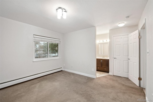 5875 E Iliff Ave Unit 108, Denver, CO 80222 - unfurnished bedroom with light colored carpet, a baseboard radiator, baseboards, ensuite bathroom, and a sink