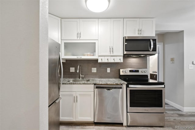 5875 E Iliff Ave Unit 108, Denver, CO 80222 - kitchen featuring appliances with stainless steel finishes, a sink, light stone countertops, white cabinets, and tasteful backsplash