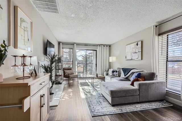 living room with a textured ceiling, dark wood-type flooring, and visible vents