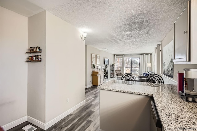 kitchen featuring a peninsula, wood finished floors, a textured ceiling, visible vents, and baseboards