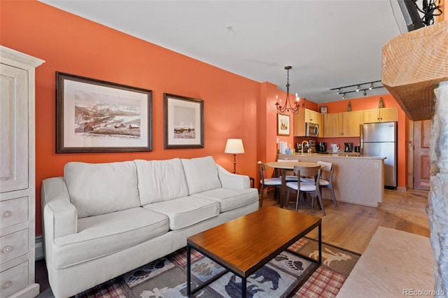 living room featuring light wood-style flooring, a chandelier, and track lighting