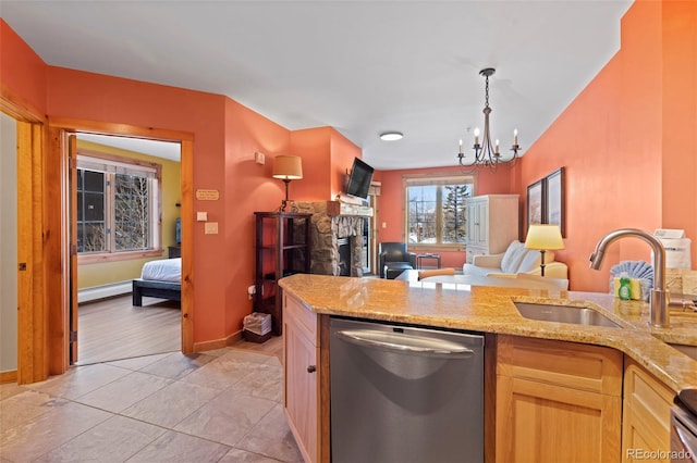 kitchen featuring open floor plan, light stone counters, a stone fireplace, stainless steel dishwasher, and a sink