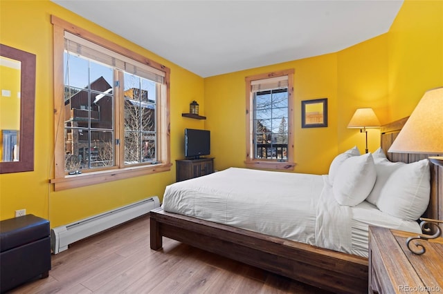 bedroom with wood finished floors and a baseboard radiator