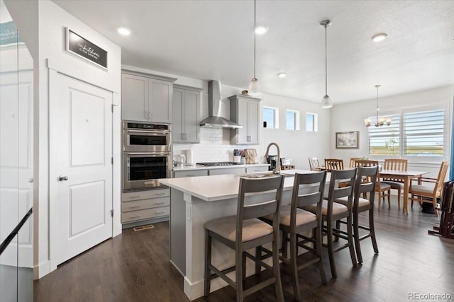 13476 Willow St, Thornton, CO 80602 - kitchen featuring wall chimney range hood, gray cabinets, stainless steel appliances, dark wood finished floors, and recessed lighting