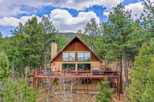 2169 Spruce Rd, Woodland Park, CO 80863 - back of property with a chimney, a wooden deck, and stucco siding
