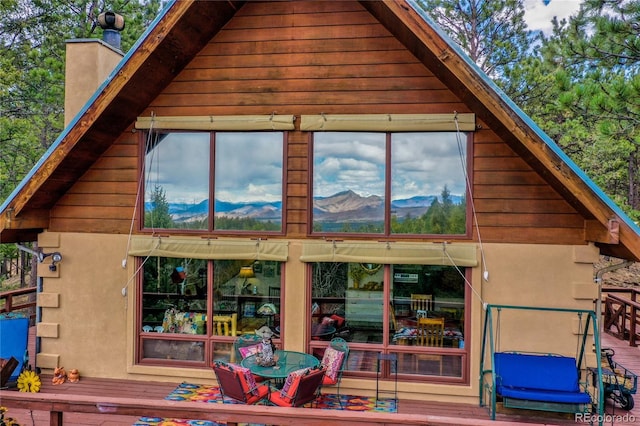2169 Spruce Rd, Woodland Park, CO 80863 - back of property featuring a chimney, a deck with mountain view, and stucco siding