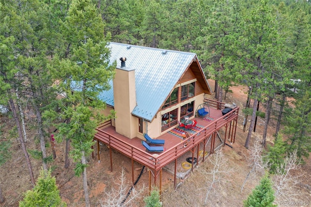 2169 Spruce Rd, Woodland Park, CO 80863 - rear view of house featuring a wooden deck, a metal roof, a chimney, stucco siding, and a forest view