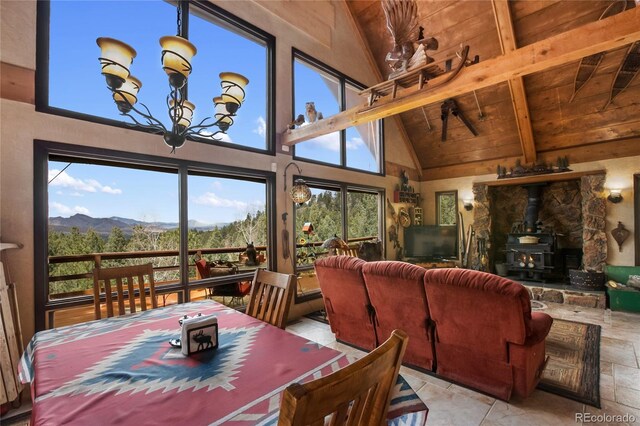 2169 Spruce Rd, Woodland Park, CO 80863 - dining room with high vaulted ceiling, a wood stove, a mountain view, a wood ceiling with exposed beams, and a chandelier