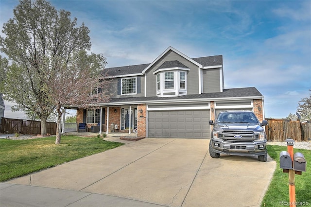 traditional home with concrete driveway, a front lawn, covered porch, fence, and brick siding