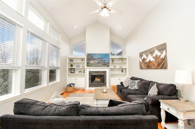 living area featuring light wood-type flooring, high vaulted ceiling, ceiling fan, and plenty of natural light