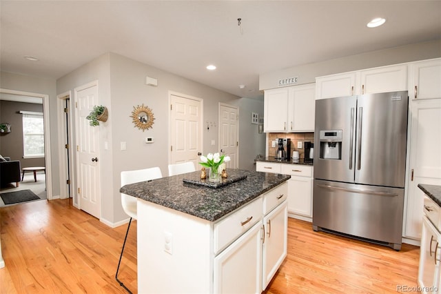 kitchen with light wood-style floors, stainless steel fridge, recessed lighting, and a breakfast bar area