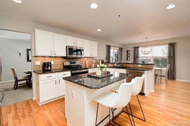 kitchen featuring a chandelier, a sink, a kitchen island, a peninsula, and appliances with stainless steel finishes