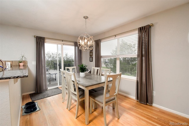 dining room with light wood-style flooring, baseboards, a notable chandelier, and plenty of natural light