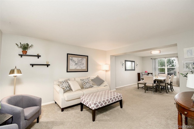 living area with baseboards and light colored carpet