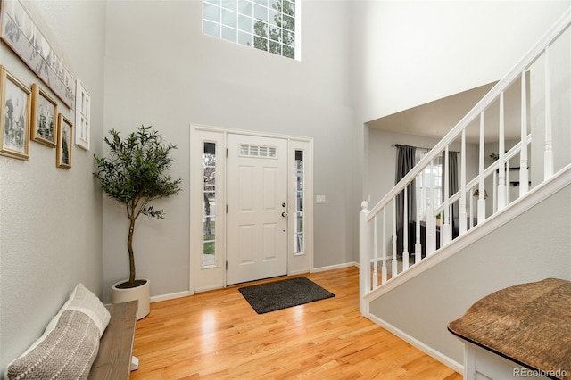 entrance foyer with baseboards, wood finished floors, a towering ceiling, and stairs