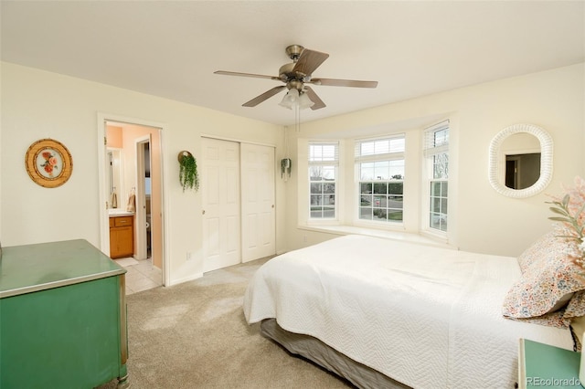 bedroom featuring a ceiling fan, light carpet, ensuite bath, a closet, and baseboards