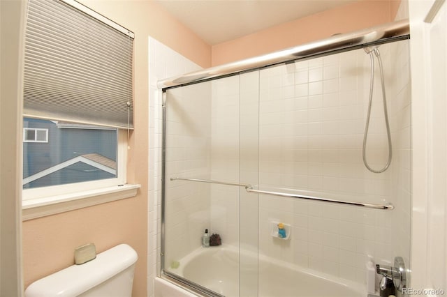 full bath featuring toilet and bath / shower combo with glass door