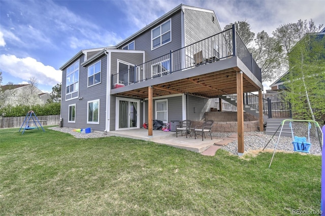 back of property with a patio area, a playground, a deck, fence, and a yard