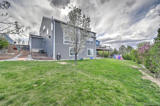rear view of property featuring a yard, central AC unit, and a deck