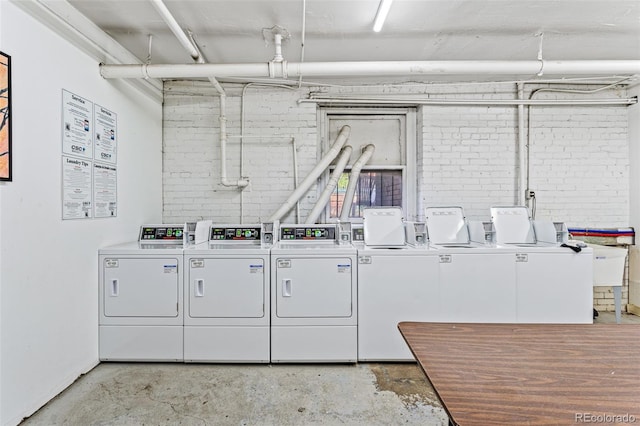 common laundry area with separate washer and dryer and brick wall