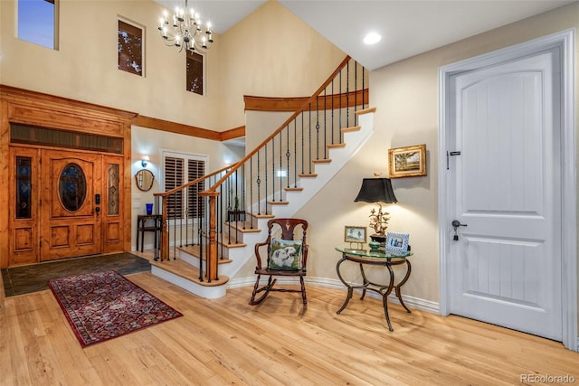 foyer featuring a towering ceiling, a notable chandelier, and light wood-type flooring