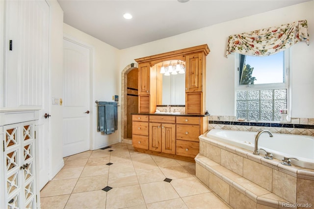 bathroom featuring a relaxing tiled bath, vanity, and tile floors