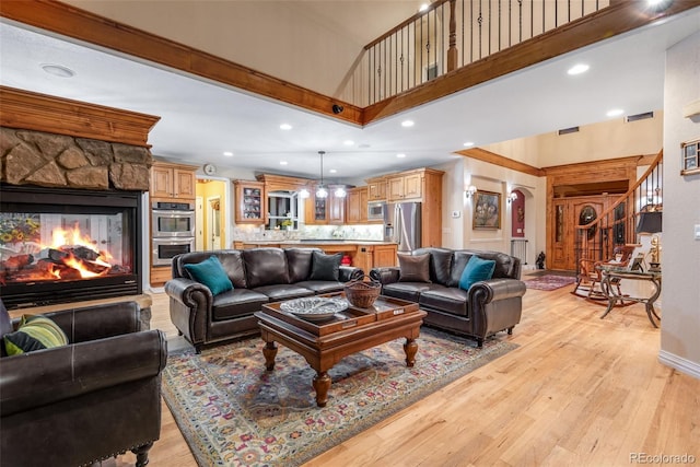 living room featuring light hardwood / wood-style flooring, a towering ceiling, and a fireplace