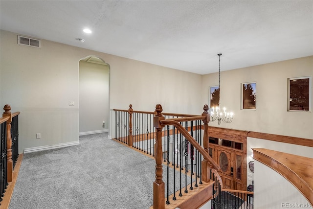 hall featuring a chandelier and carpet