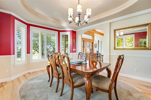 dining room with an inviting chandelier, light wood-type flooring, ornamental molding, and a tray ceiling