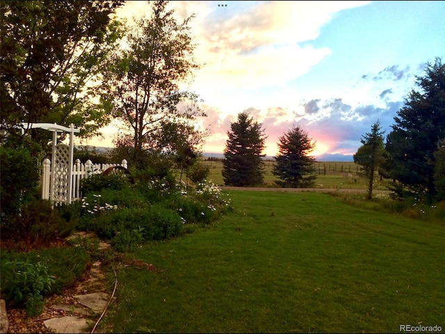 yard at dusk featuring a rural view