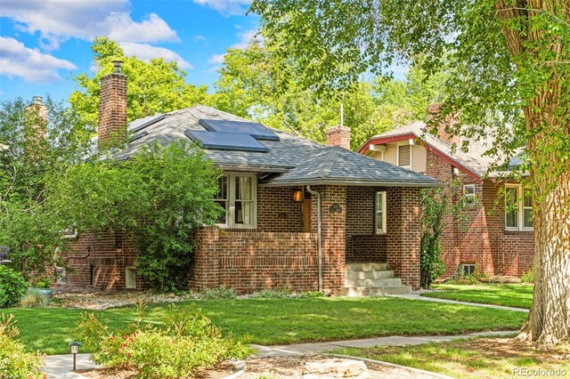 2271 Holly St, Denver, CO 80207 - view of front of property featuring a chimney, roof mounted solar panels, brick siding, and a front yard