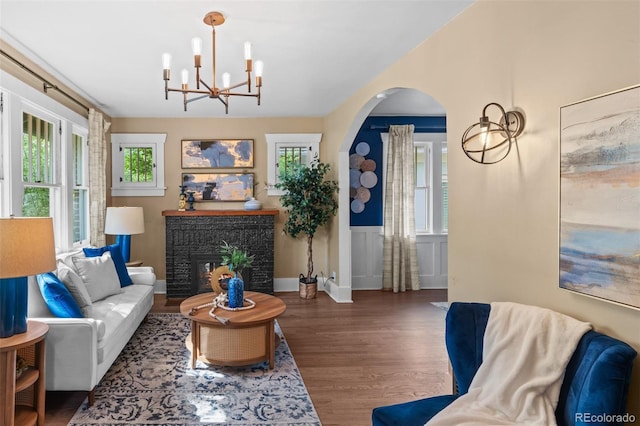 2271 Holly St, Denver, CO 80207 - living room featuring a chandelier, wood finished floors, healthy amount of natural light, arched walkways, and wainscoting